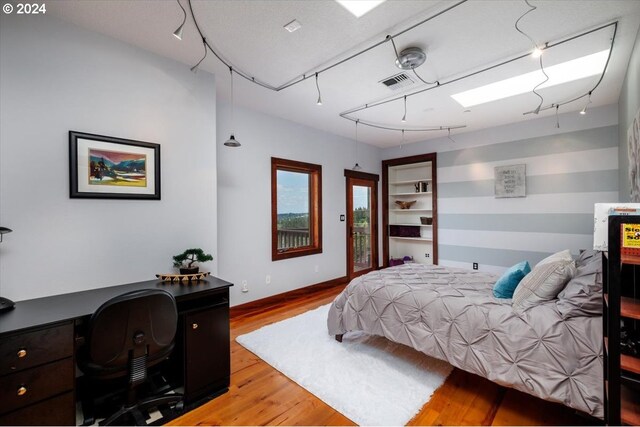 bedroom featuring access to outside, track lighting, and light hardwood / wood-style flooring