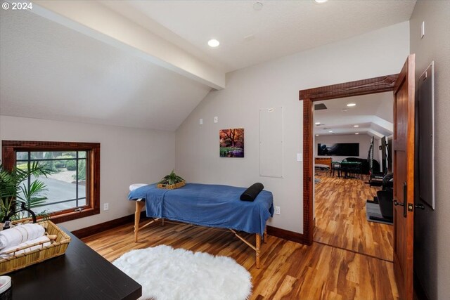 bedroom with vaulted ceiling with beams and wood-type flooring