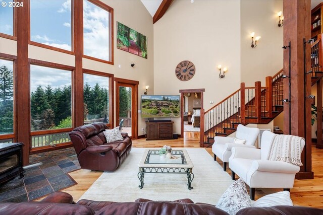 living room featuring wood-type flooring, high vaulted ceiling, and a wood stove