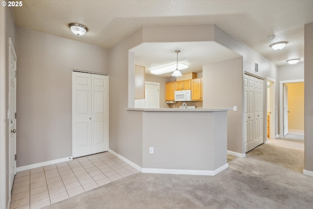 kitchen with light colored carpet, kitchen peninsula, and light brown cabinets