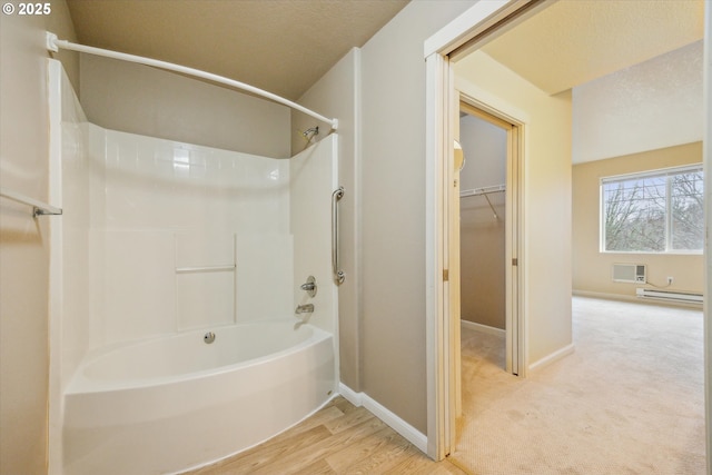 bathroom with wood-type flooring, a baseboard heating unit, and  shower combination