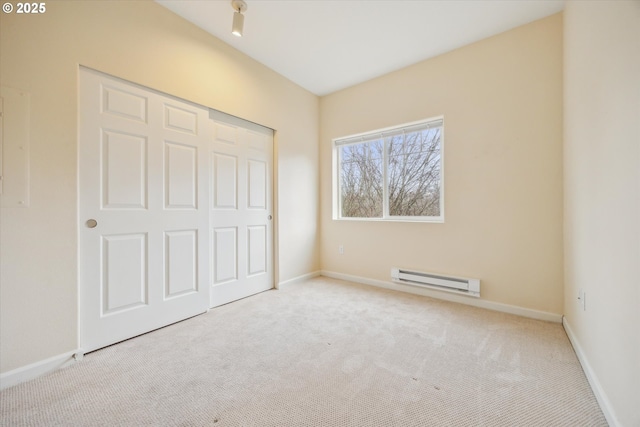 unfurnished bedroom with light colored carpet, a baseboard heating unit, and a closet