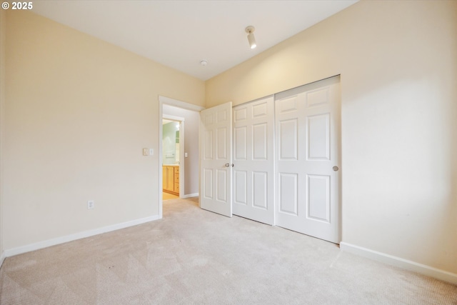 unfurnished bedroom featuring light carpet and a closet