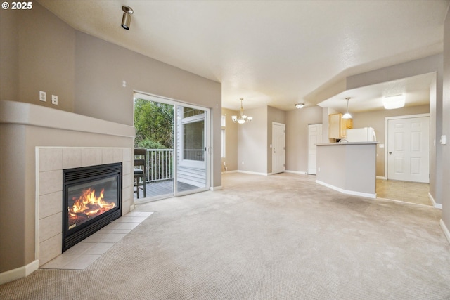 unfurnished living room featuring light colored carpet, a tile fireplace, and a chandelier