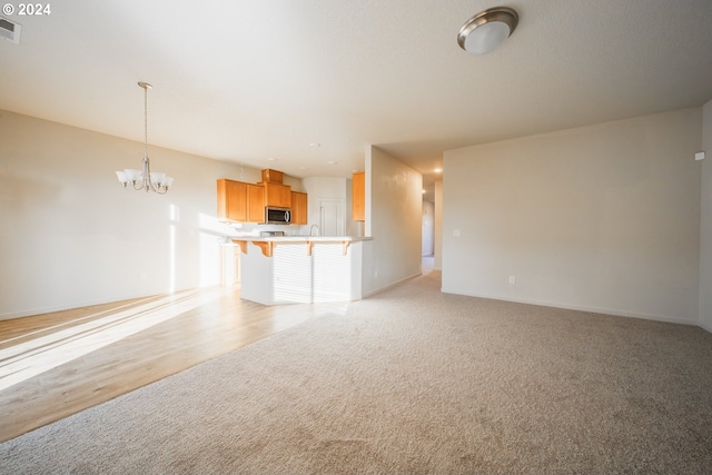 unfurnished living room with a chandelier and light hardwood / wood-style flooring