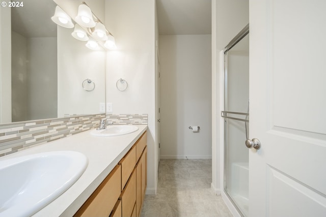 bathroom with vanity, a shower with shower door, and tasteful backsplash