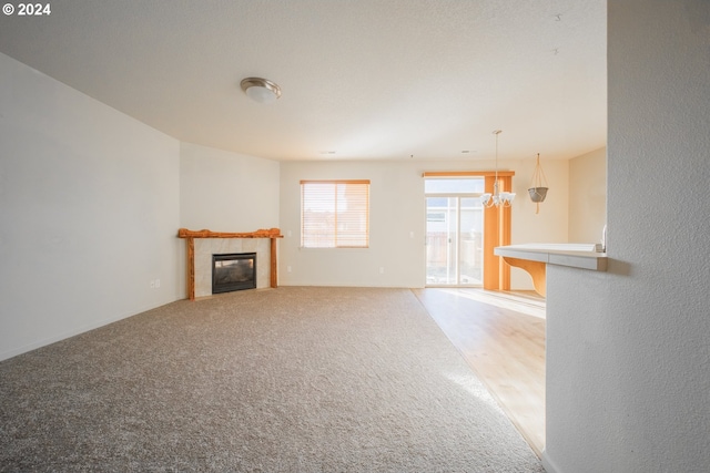 unfurnished living room with a notable chandelier, carpet flooring, and a fireplace