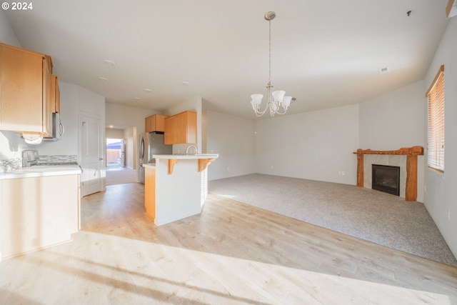 kitchen featuring a breakfast bar, a tile fireplace, light hardwood / wood-style floors, a notable chandelier, and decorative light fixtures