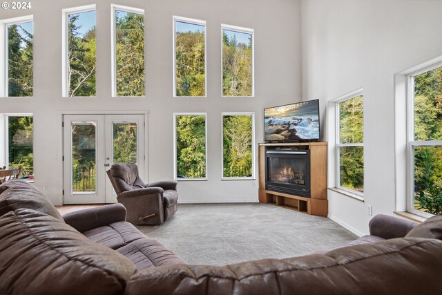 carpeted living room with a high ceiling and french doors