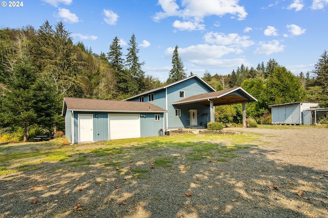 view of front facade with a carport, driveway, a porch, and an outbuilding