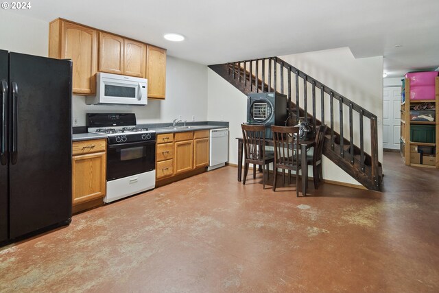 kitchen featuring washer / dryer, sink, white appliances, and concrete flooring