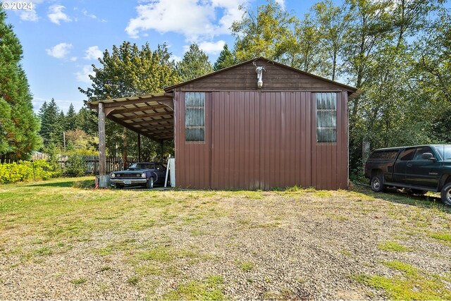 view of side of home with a yard, a carport, and an outbuilding