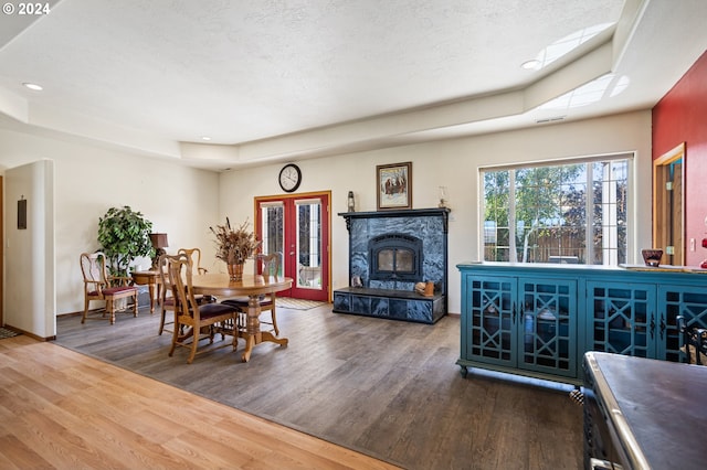 living room with a tray ceiling, a premium fireplace, hardwood / wood-style floors, and a textured ceiling