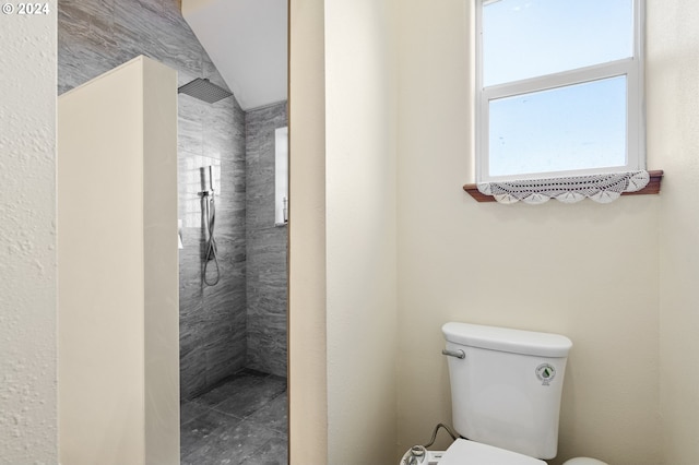 bathroom featuring lofted ceiling, toilet, and tiled shower