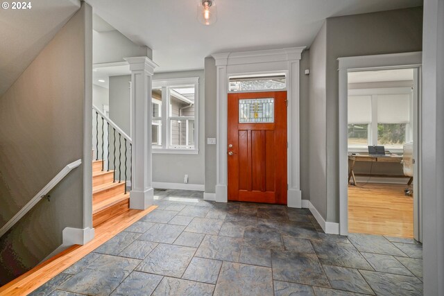 foyer featuring wood-type flooring, a wealth of natural light, and decorative columns