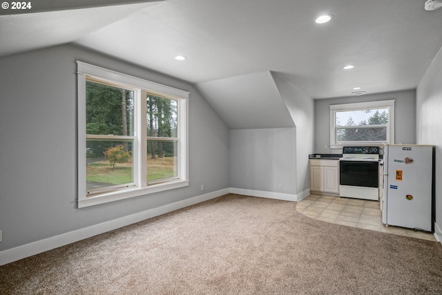 kitchen featuring a wealth of natural light, light colored carpet, range with electric cooktop, and freestanding refrigerator