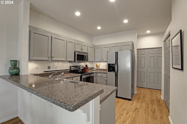 kitchen with light hardwood / wood-style floors, kitchen peninsula, sink, gray cabinets, and stainless steel appliances