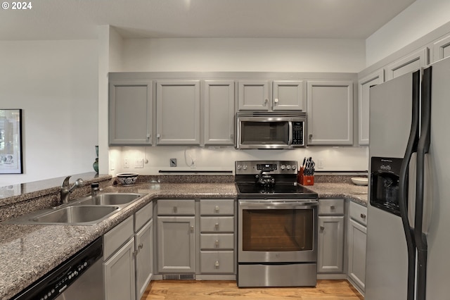 kitchen with gray cabinetry, light wood-type flooring, sink, and appliances with stainless steel finishes