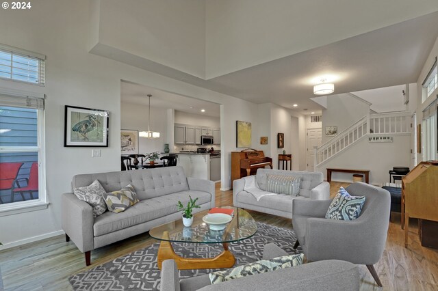 living room with a healthy amount of sunlight, a towering ceiling, and light hardwood / wood-style floors