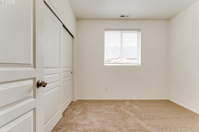 unfurnished bedroom featuring light carpet and a closet