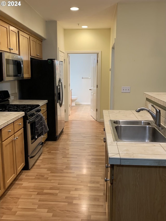 10733 NE Red Wing Way Unit 101, Hillsboro, OR 97006 - kitchen featuring stainless steel appliances, a sink, tile counters, light wood finished floors, and recessed lighting