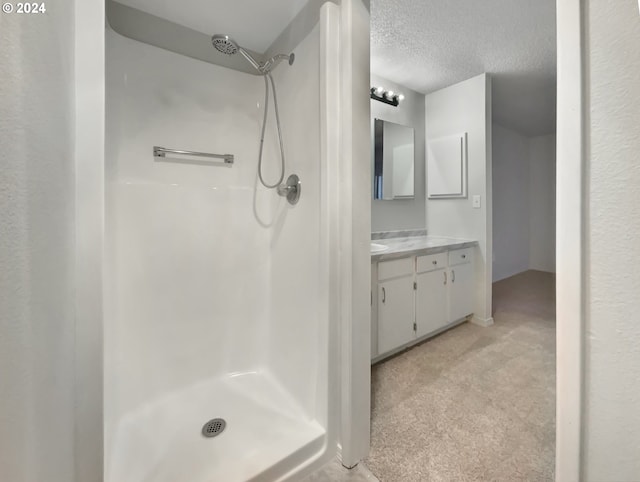 bathroom featuring vanity, a textured ceiling, and walk in shower