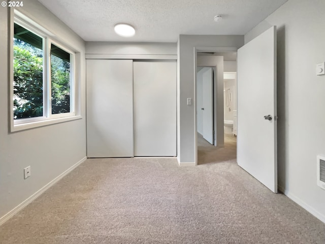 unfurnished bedroom featuring a closet, light colored carpet, and a textured ceiling