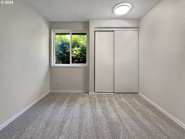 unfurnished bedroom with carpet, a textured ceiling, and a closet