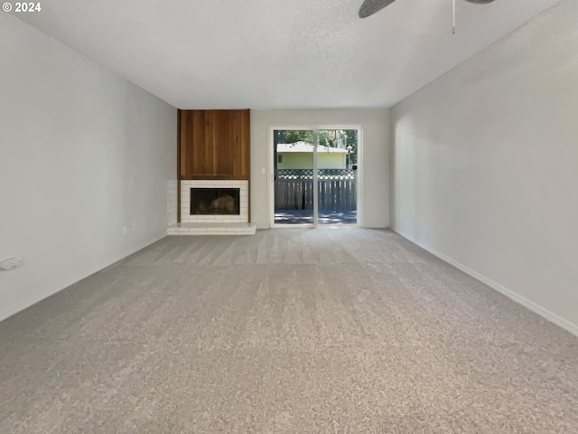 unfurnished living room with ceiling fan, carpet, a textured ceiling, and a brick fireplace