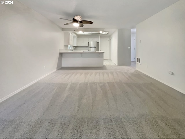 unfurnished living room featuring ceiling fan and light colored carpet