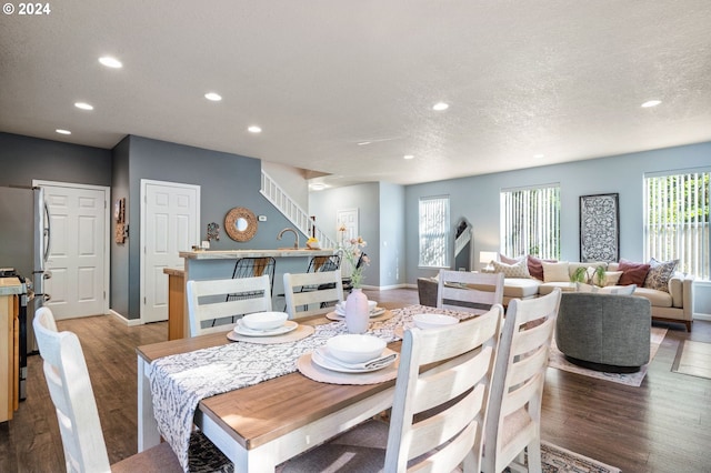 dining space featuring plenty of natural light, sink, wood-type flooring, and a textured ceiling