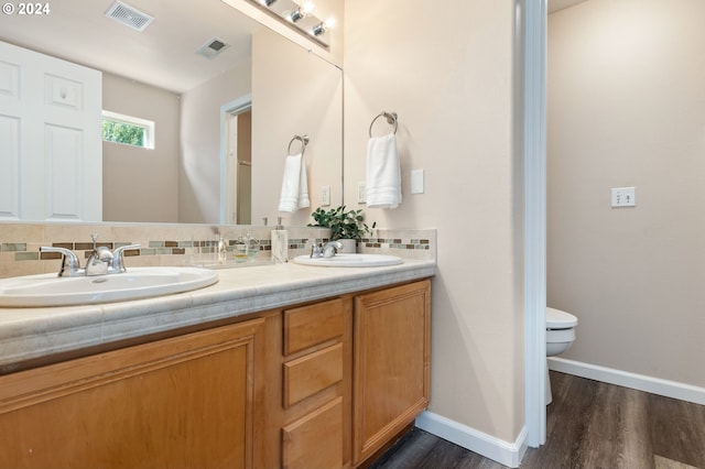 bathroom with vanity, toilet, wood-type flooring, and tasteful backsplash