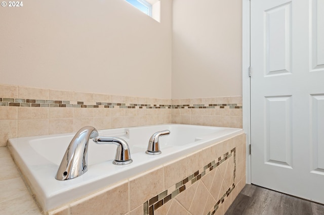 bathroom featuring tiled tub and hardwood / wood-style floors