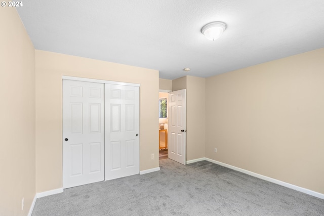 unfurnished bedroom featuring light carpet and a closet