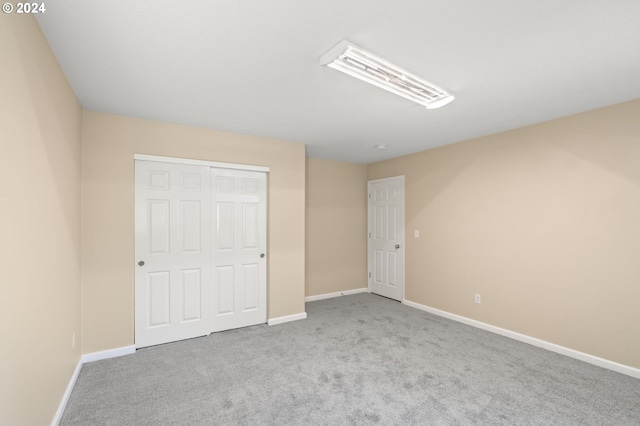 unfurnished bedroom featuring light colored carpet and a closet