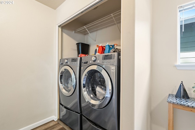 clothes washing area with wood-type flooring, washing machine and clothes dryer, and a healthy amount of sunlight