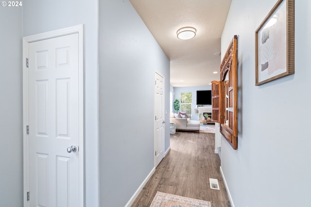 hall with wood-type flooring and a textured ceiling