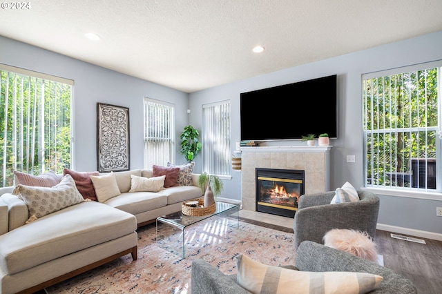 living room featuring hardwood / wood-style flooring, a tiled fireplace, and plenty of natural light