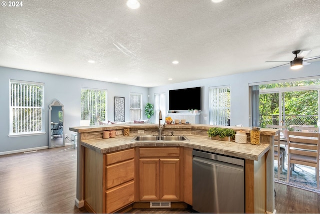 kitchen featuring a wealth of natural light, a kitchen island with sink, sink, and stainless steel dishwasher