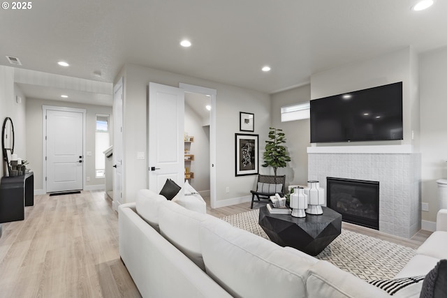 living room with recessed lighting, a fireplace, visible vents, baseboards, and light wood-type flooring