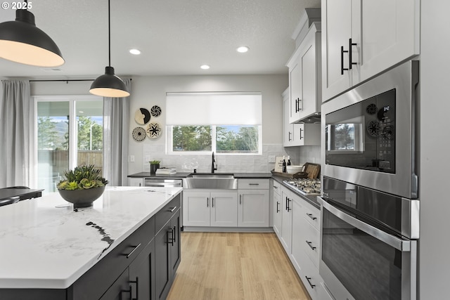 kitchen featuring light wood-style floors, stainless steel gas cooktop, a sink, and backsplash