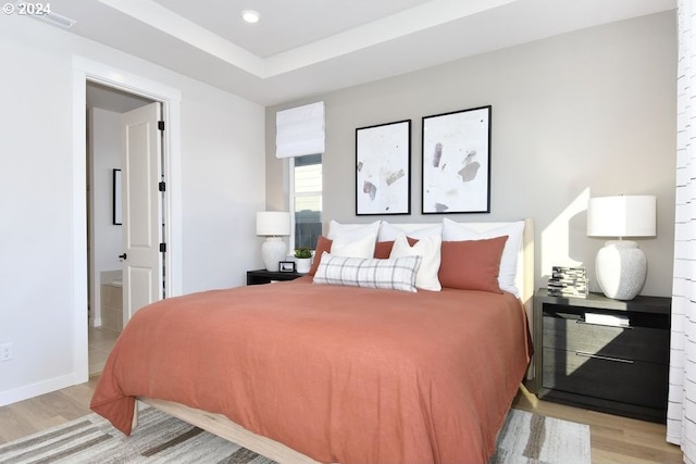 bedroom featuring light hardwood / wood-style floors and ensuite bath