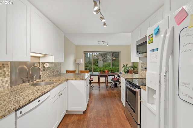 kitchen featuring light stone counters, kitchen peninsula, appliances with stainless steel finishes, white cabinets, and dark hardwood / wood-style flooring