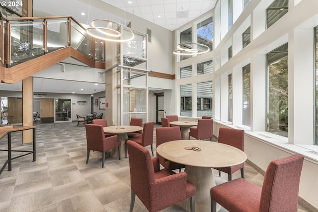 dining space with light carpet, a chandelier, and a high ceiling