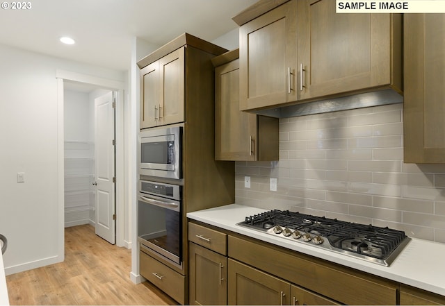 kitchen featuring stainless steel appliances, light hardwood / wood-style floors, and tasteful backsplash