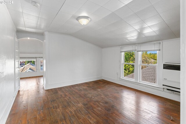 interior space featuring dark wood-type flooring, vaulted ceiling, and heating unit