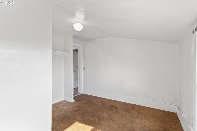 carpeted spare room with vaulted ceiling