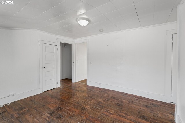 unfurnished room featuring crown molding and dark wood-type flooring