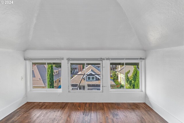 spare room featuring dark hardwood / wood-style flooring, lofted ceiling, and a textured ceiling