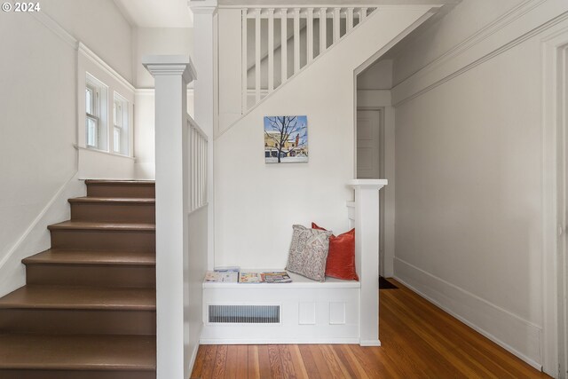 stairs with wood-type flooring and decorative columns